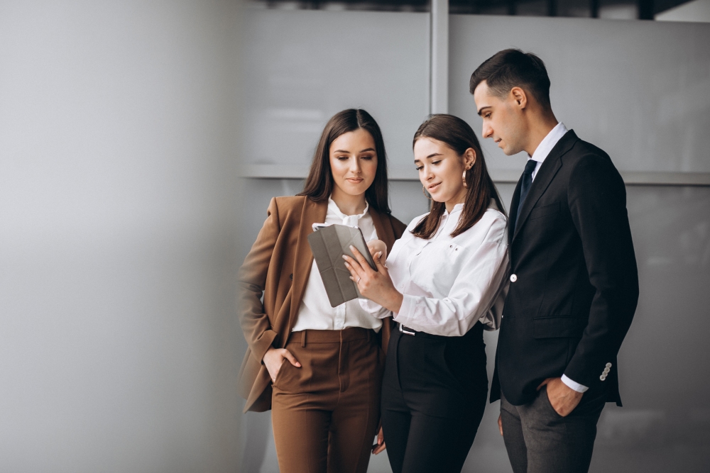 Three business professionals reviewing corporate registration details on a digital tablet